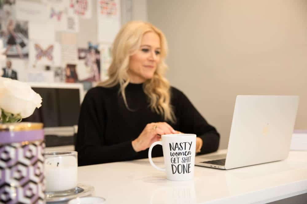 image of brand strategist and branding coach Liz Dennery sitting at her desk near a mug that says nasty women get shit done