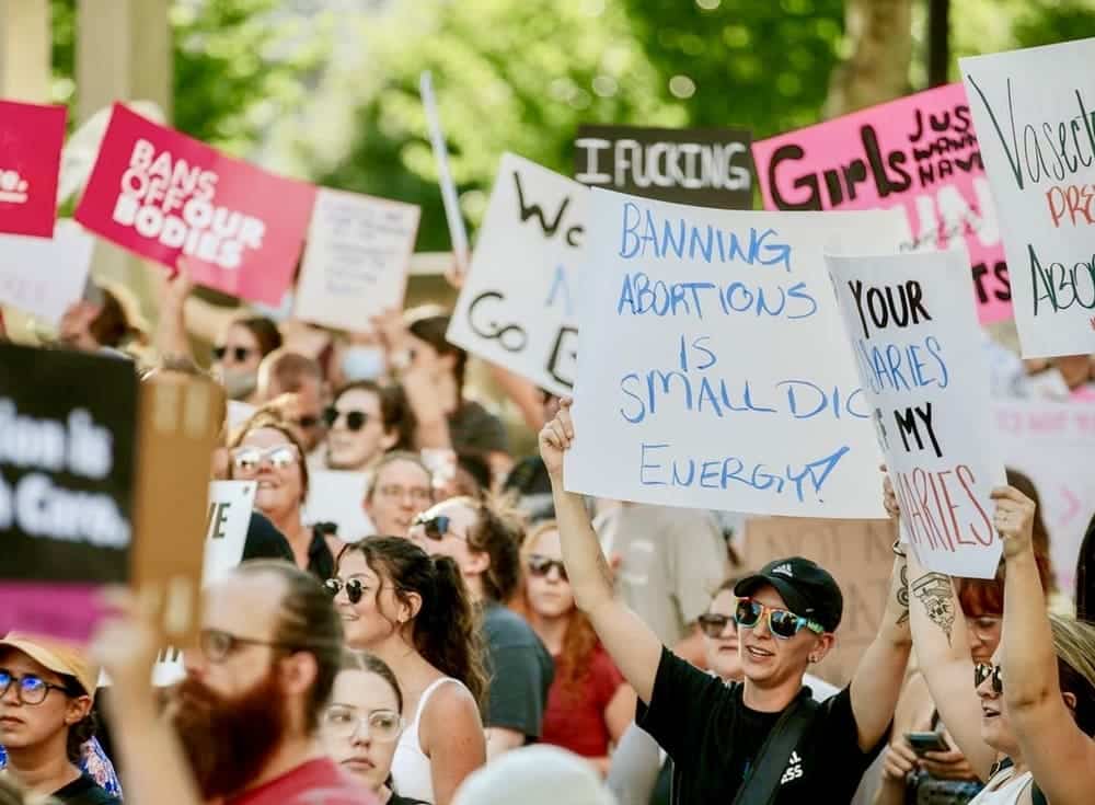 it's more important than ever to build your brand - image of women and men protesting against abortion bans amid Supreme Court roe vs wade decision with signs that say banning abortions is small dick energy and bans off our bodies