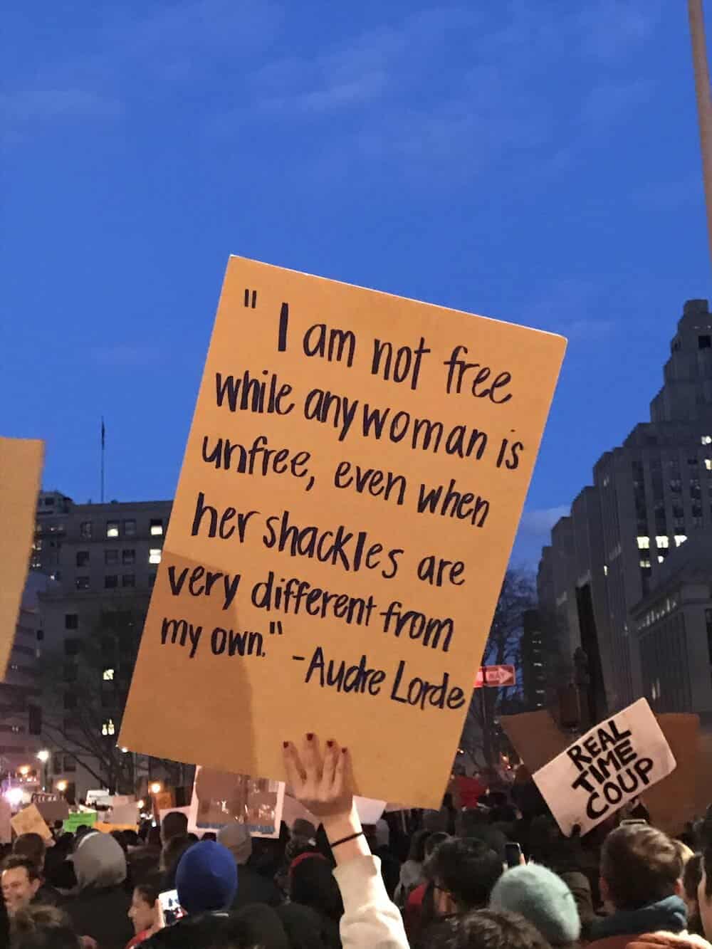 image of women's rights protester with sign that says I am not free while any woman is unfree, even when her shackles are very different from my own - Audra Lorde